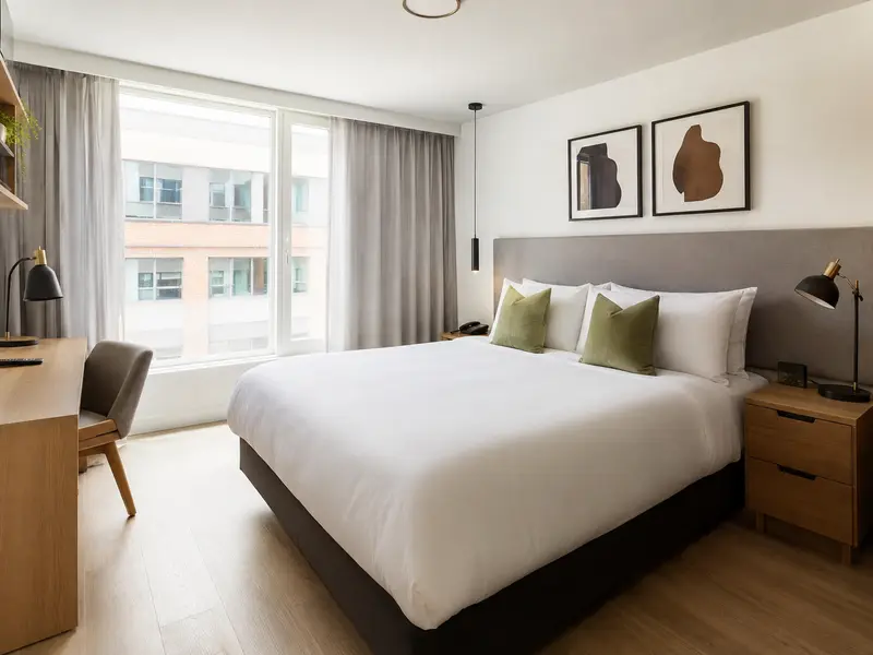 Serviced apartment bedroom with standardized hotel linens