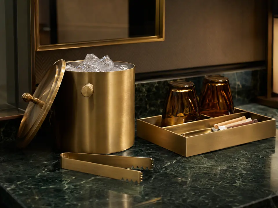 Brushed brass guest room accessories on stone
