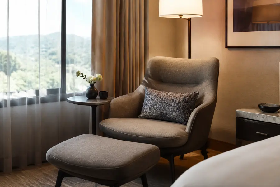 Supportive hotel lounge chair with ottoman and side table