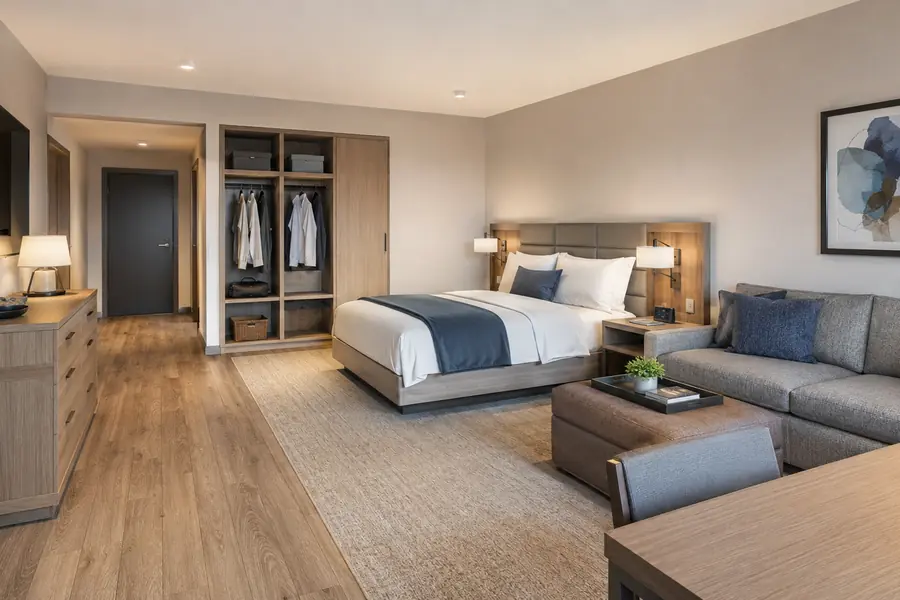 Extended-stay hotel room with wardrobe, dresser, work table, and sofa