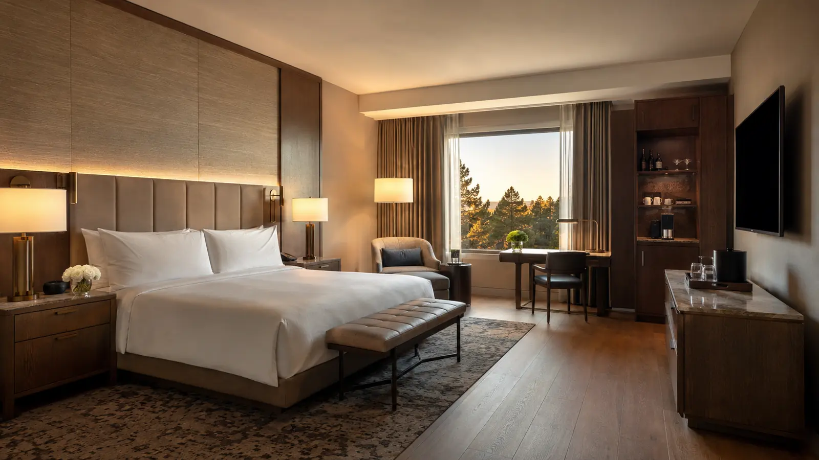 Coordinated commercial hotel guest room with upholstered bed, headboard, nightstands, desk, lounge seating, and casegoods