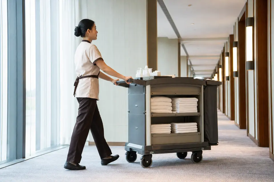 Hotel attendant pushing an ergonomically configured housekeeping cart